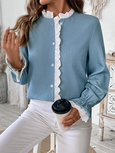 Detailed view of white lace trim on cuffs and collar of light blue linen shirt