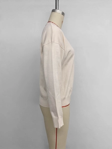 Detail of rib-knit cuffs and hem on a minimalist apricot crewneck sweater