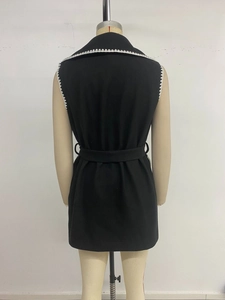 Détail du long gilet noir avec bordure festonnée blanche et ceinture assortie