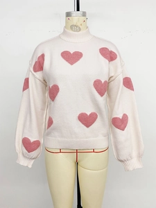 Detailaufnahme von rosa Herz-Jacquardmuster auf cremeweißem Strickpullover mit Rippbündchen