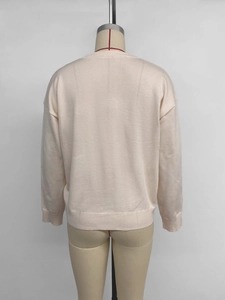 Detail view of cream knit sweater showing ribbed cuffs and high-quality fabric texture