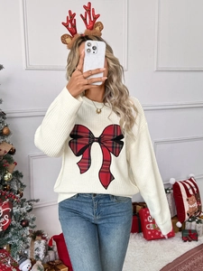 Close-up of white knit sweater featuring a large red plaid bow for Christmas style