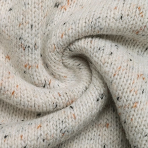Close-up of chunky knit cardigan showing soft grey fabric with orange and black accents