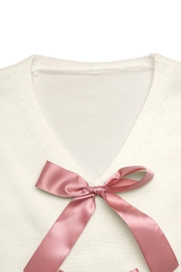 Detail eines V-Ausschnitt Strickpullovers mit einer zarten rosa Satinschleife