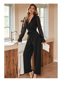 Detail of black jumpsuit showing sheer mesh sleeve texture and V-neckline finish