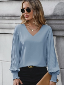 Detail of V-neck dusty blue blouse with pleated lantern sleeves and ruffled elastic cuffs