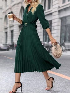 Détail d'une robe midi plissée vert foncé avec col en V et ceinture à boucle dorée