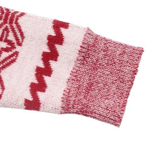 Detail of red and pink knitted sweater featuring ribbed cuffs and snowflake jacquard texture