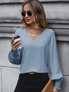 Detail of light blue shirt featuring fine pleated lantern sleeves and V-neckline design
