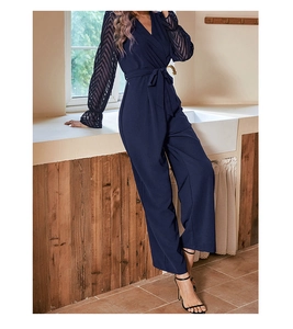 Detail of navy blue V-neck jumpsuit featuring hollowed-out wavy texture sleeves and waist tie