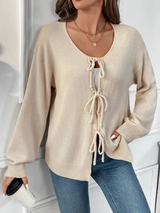 Detail der cremefarbenen Strickjacke mit drei vorderen Bändern und einem V-Ausschnitt