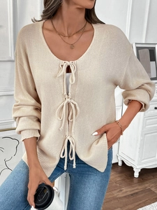 Detailansicht der beige gestrickten Strickjacke mit stilvollen Bindebändern und weicher Textur