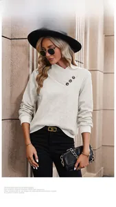 Close-up of white waffle knit sweater featuring cross V-neck and decorative black buttons
