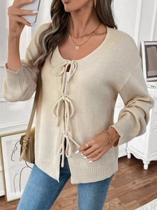 Detailansicht der cremefarbenen Strickjacke mit Schleifen und Rippenbündchen