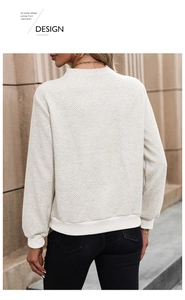 Detail view of beige sweatshirt showing geometric twill texture and ribbed cuffs for women