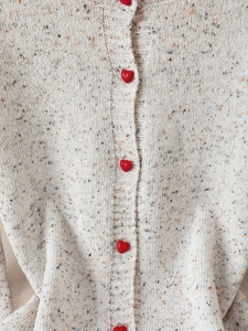 Elegant off-white knit cardigan with colorful tweed texture and red heart-shaped buttons
