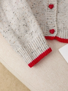 Detailed macro shot of vintage knit cardigan with red heart buttons and ribbed edges