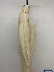 Detailansicht der beigen Strickjacke mit Schnürung vorne und gerippten Ärmelbündchen