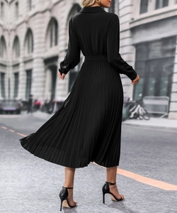Détail d'une robe noire à manches longues plissée avec ceinture assortie et jupe en mousseline