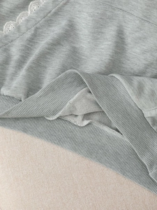 Close-up of light gray sweatshirt featuring white lace trim and ribbed hem detail