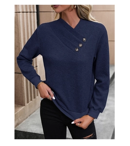 Detail of navy blue waffle knit sweater featuring a crisscross V-neck and button accents