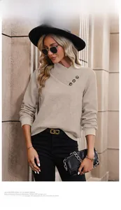 Detail of apricot textured knit sweater with crossover neckline and decorative buttons
