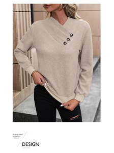 Detail of light beige long sleeve sweatshirt with diamond textured fabric and buttoned V-neck