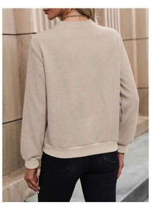 Detail of beige sweatshirt featuring diamond quilted texture and ribbed cuffs on back view