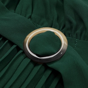 Vue macro détaillée des plis avec boucle en résine sur la robe vert foncé