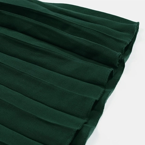Détails d'une robe plissée vert foncé montrant la texture fine et l'ourlet précis