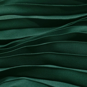 Gros plan sur la texture du tissu plissé vert foncé aux plis verticaux élégants