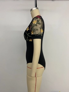 Detail of sheer mesh sleeves featuring colorful floral embroidery on a black bodysuit
