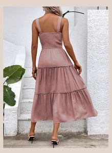 Outdoor back view of a dusty pink smocked dress with a tiered summer midi skirt