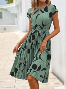 Détail d'une robe plissée vert sauge avec motifs abstraits noirs et ceinture à la taille