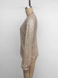 Macro detail of champagne gold sequins on long sleeve shirt showing vertical patterns