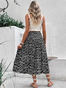 Detail of a white pleated crop top and black floral midi skirt for a summer resort look