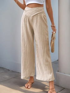 Detail of high waisted wide leg trousers featuring a V-shaped waist and pleated texture