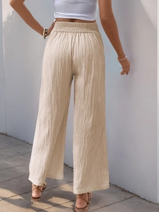 Close-up of beige high-waist wide-leg pants showing elastic waistband and pleated texture