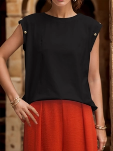 Detail of elegant black sleeveless top showing gold button accents on shoulders