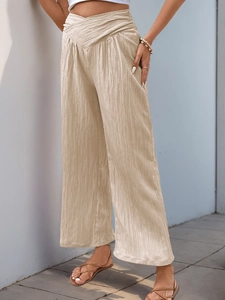 Detailed view of the V-shaped high waist and pleated texture of beige wide-leg pants