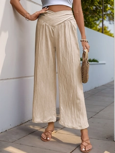 Detail view of the V-shaped cross high waist design and pleated texture of beige trousers