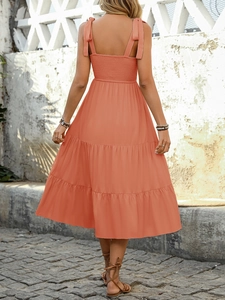 Detail of coral orange tiered dress with smocked back and adjustable tie shoulder straps