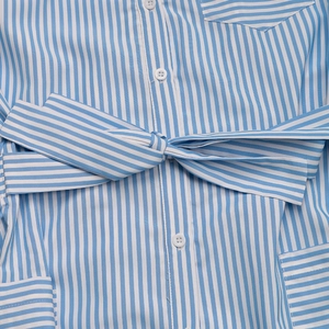 Detail of blue and white striped jumpsuit featuring button closure and waist tie bow