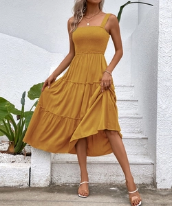 Detail of tiered ginger yellow sun dress featuring a smocked bodice and wide shoulder straps