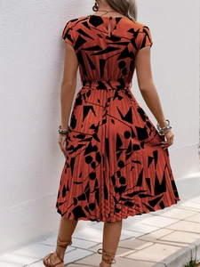 Vue détaillée du dos d'une robe plissée orange avec des motifs géométriques noirs artistiques