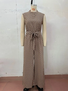 Detail of a sleeveless jumpsuit featuring blue geometric prints and a waist tie belt