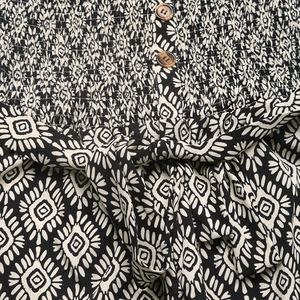 Detail of smocked bodice with wooden buttons and geometric print on wide leg jumpsuit