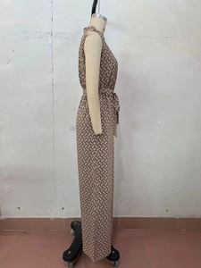 Side view of sleeveless jumpsuit featuring geometric chain print and belted waist design