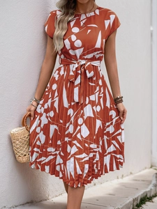 Détail de la robe plissée orange avec motifs abstraits blancs et ceinture à nouer