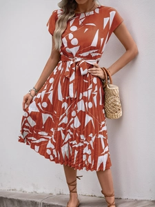 Détail de la robe plissée orange rouille avec motifs géométriques blancs et lien à nouer